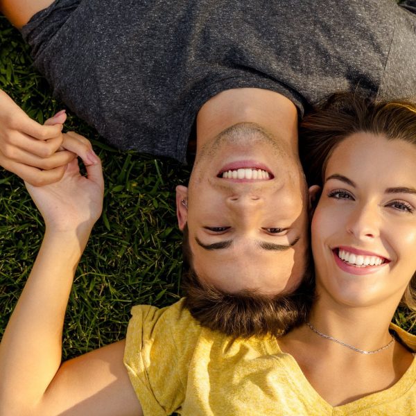 Portrait of a young beautiful couple lying on the grass